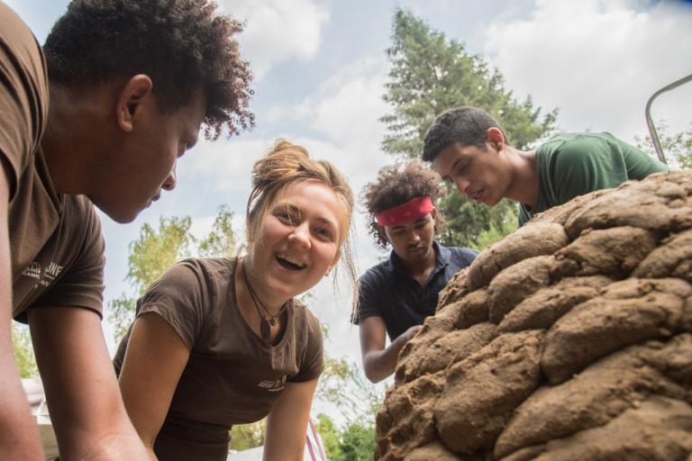 Es macht Spaß, gemeinsam einen Lehmbackofen zu bauen. | Foto: Hendrik Silbermann (ARTWORKs) Vier Teilehmende lachen, während sie neben ihrem Lehmbackofen stehen. | Foto: Hendrik Silbermann (ARTWORKs)
