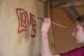 Die Bushaltestelle wird mit Inschriften versehen. Ein Mädchen malt die Buchstaben "Love" an die Wand. | Foto: Hendrik Silbermann (ARTWORKs)